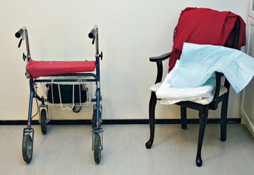 Vanhuksen elintarpeita: rollaattori, sekä tuoli, jolla huopa ja vaippa.